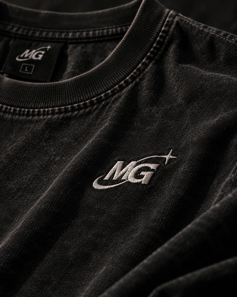 Close view of the black tee collar, fabric, and pale chest embroidery.