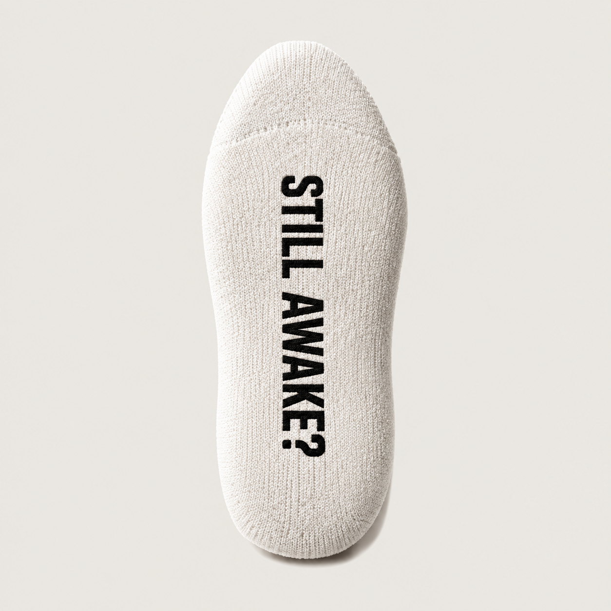 Crew Sock 01 in Vintage White, sole detail with STILL AWAKE? underneath the foot. Design concept.